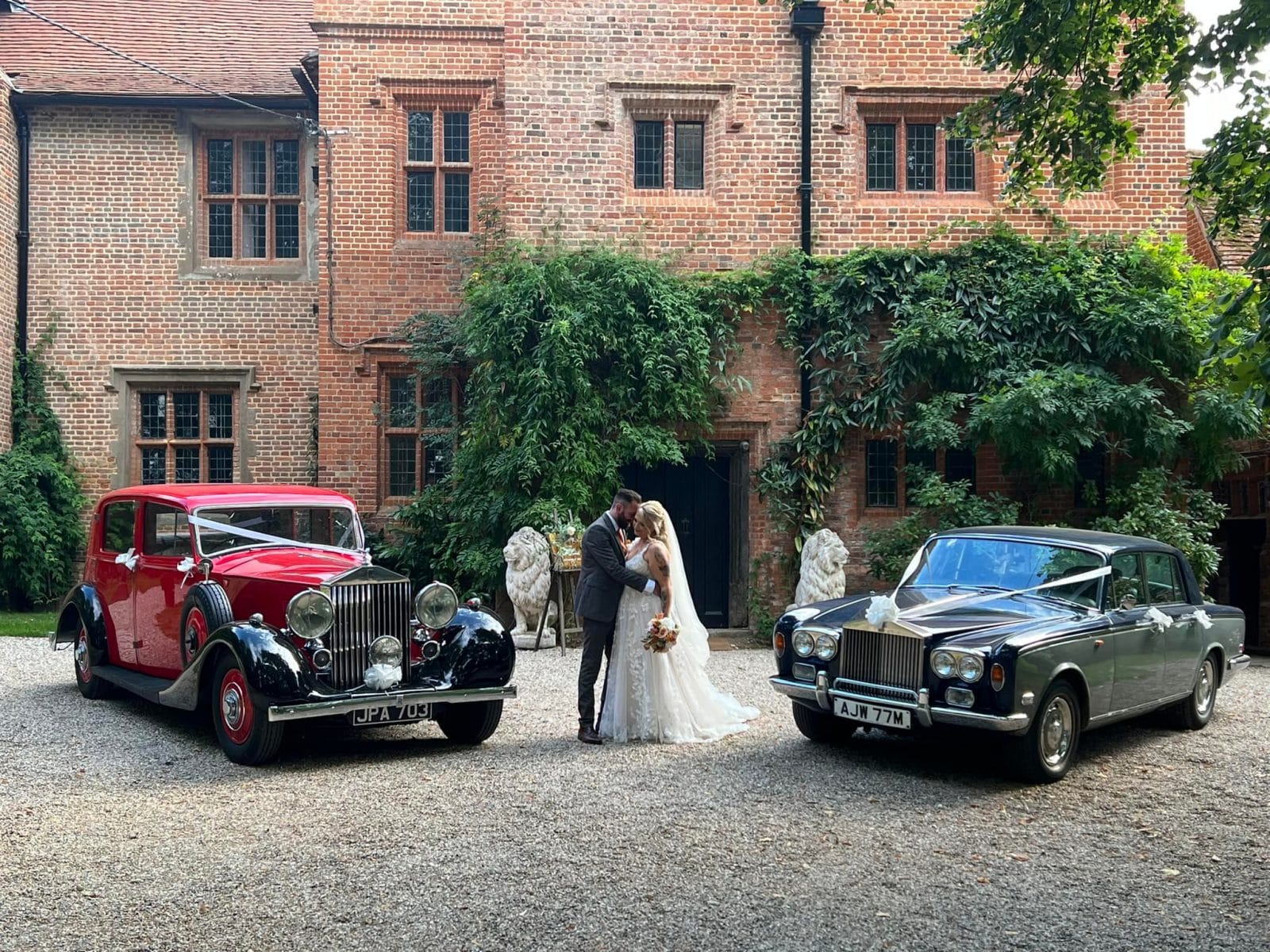 The couple with two vintage wedding cars against the Tudor facade
