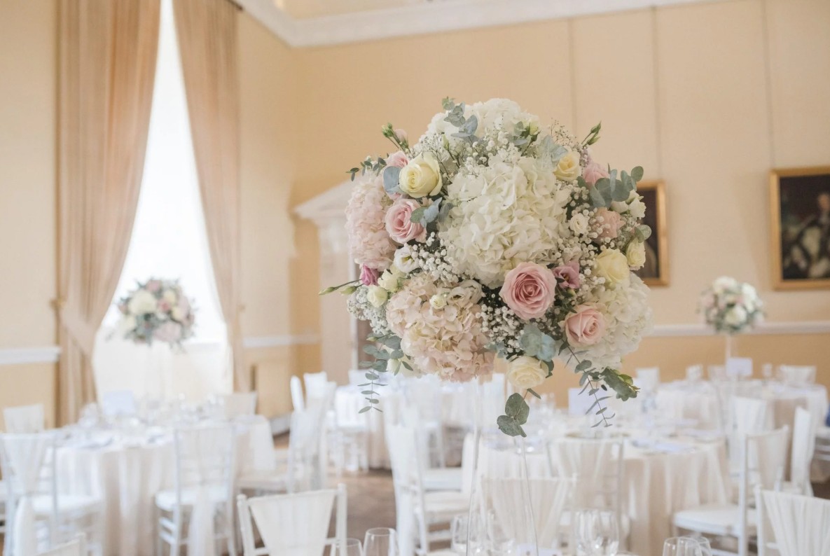 The Great Hall set for a ceremony with white chairs and tall florals