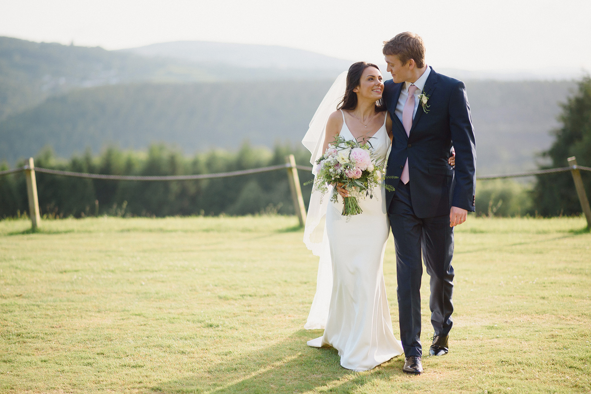 The couple walking the lawn, the valley and the moor behind them