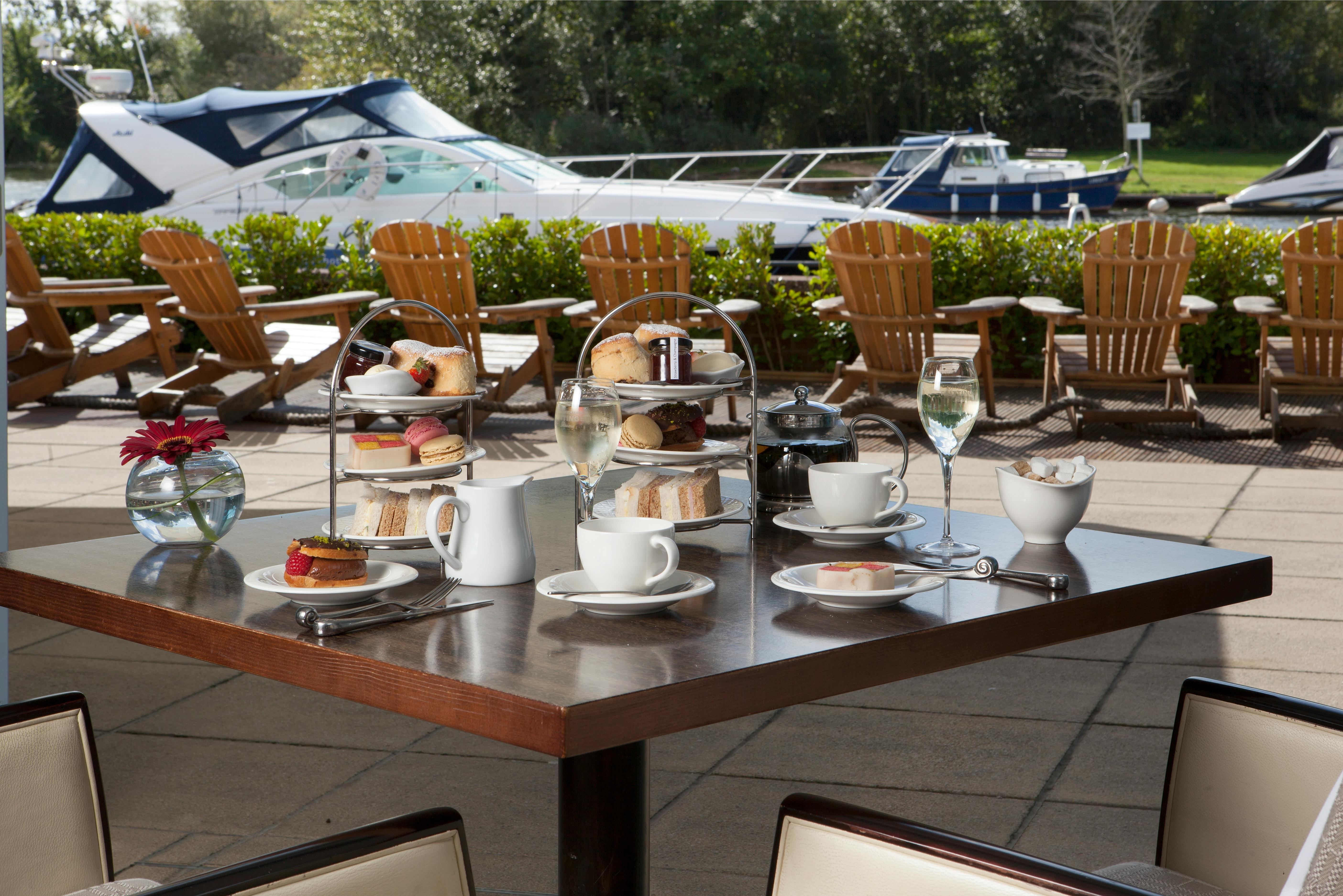 Afternoon tea on the riverside terrace with boats moored beyond