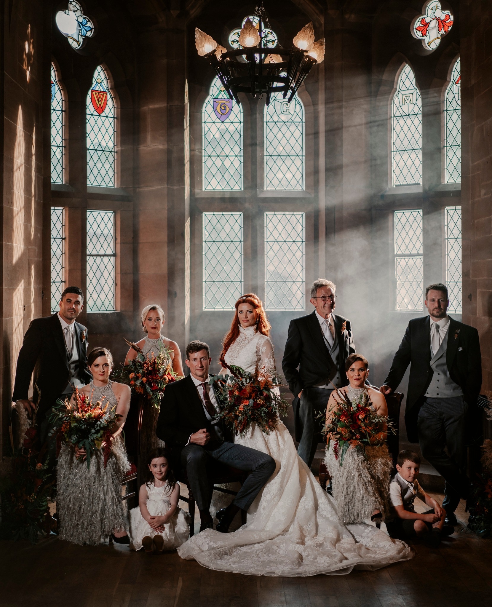 A wedding party beneath the heraldic stained-glass windows