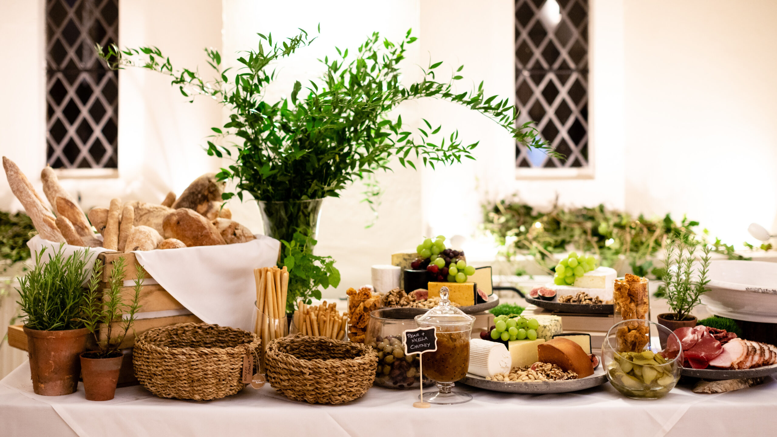 A grazing board of breads, cheeses and greenery
