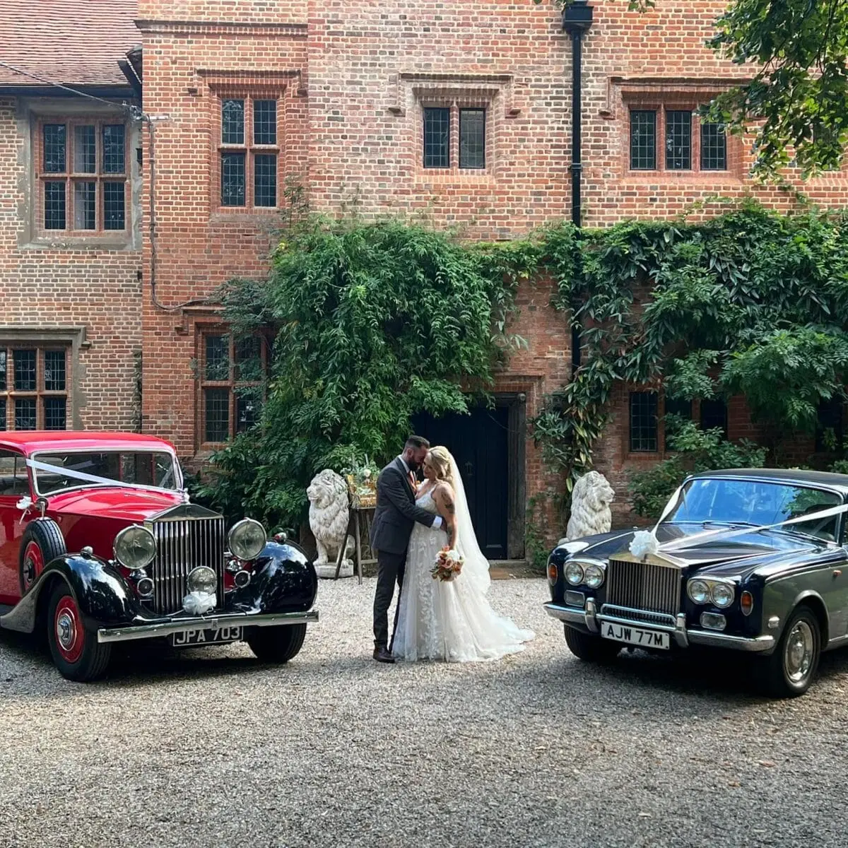 The couple with two vintage wedding cars against the Tudor facade