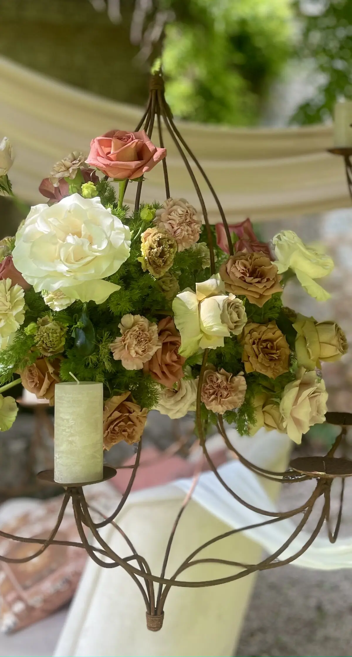 An iron chandelier hung with garden roses and pillar candles at a wedding in Umbria