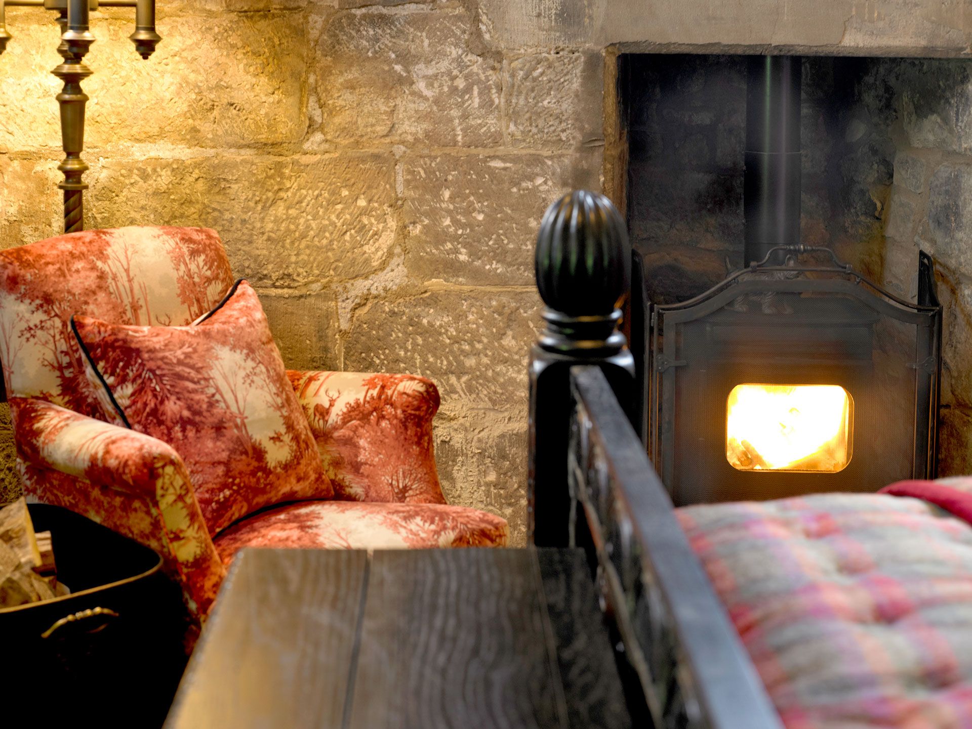 A fireside armchair beside a wood-burning stove