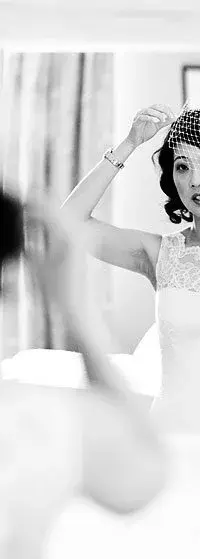 A bride adjusting her birdcage veil in the mirror, Le Manoir aux Quat'Saisons
