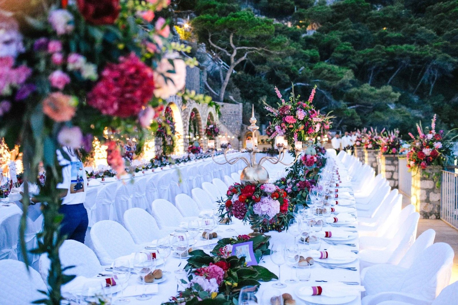 A long table under the coastal pines, pink and crimson down the middle