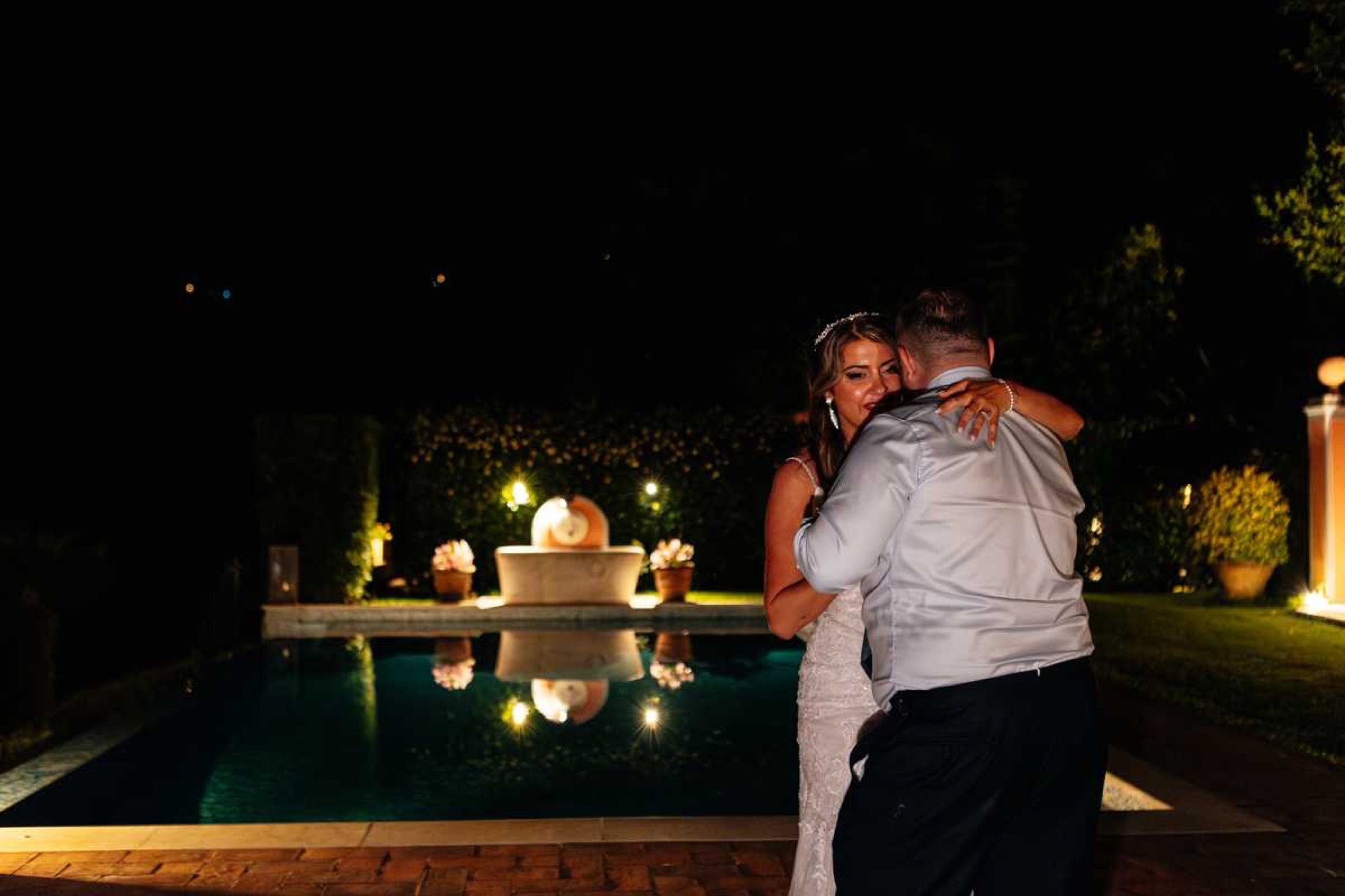 A couple by the lit pool at night