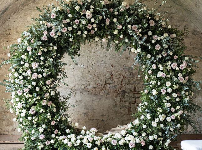 A floral wreath installation, against bare stone