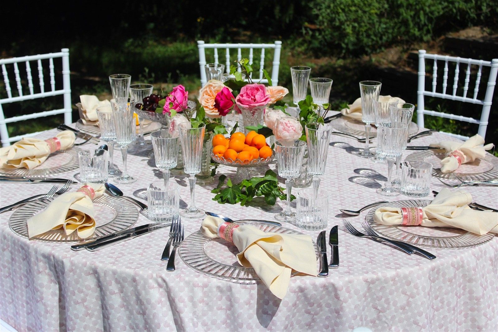 A round table in the garden, peaches and pink roses, the glasses ranked