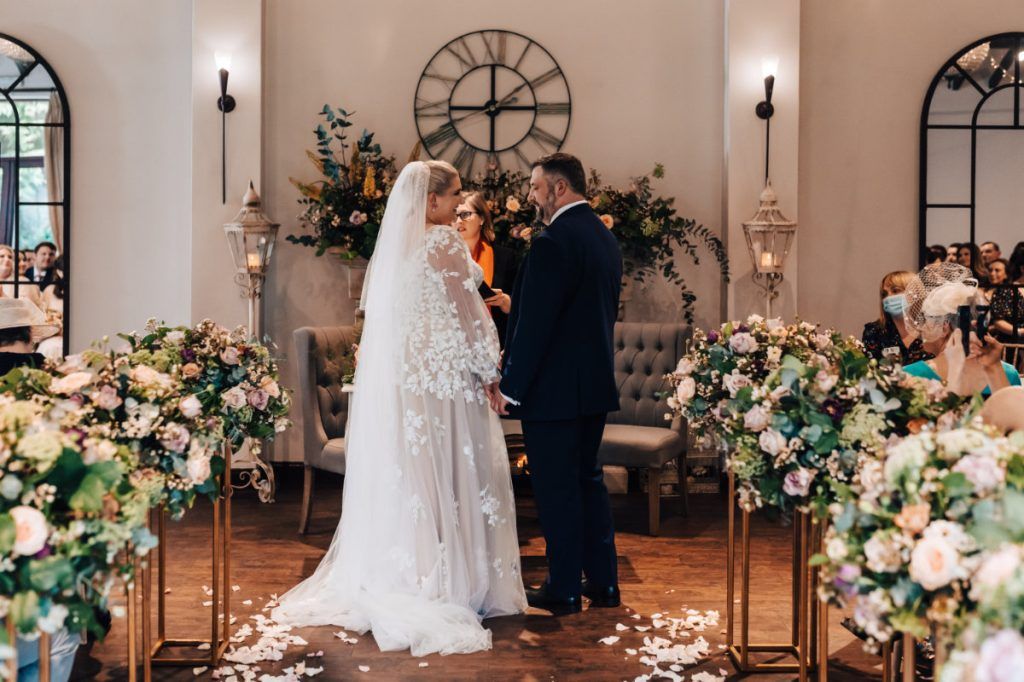 The couple exchange vows beneath a floral pedestal-lined aisle, Shilpa Reddy, London, England