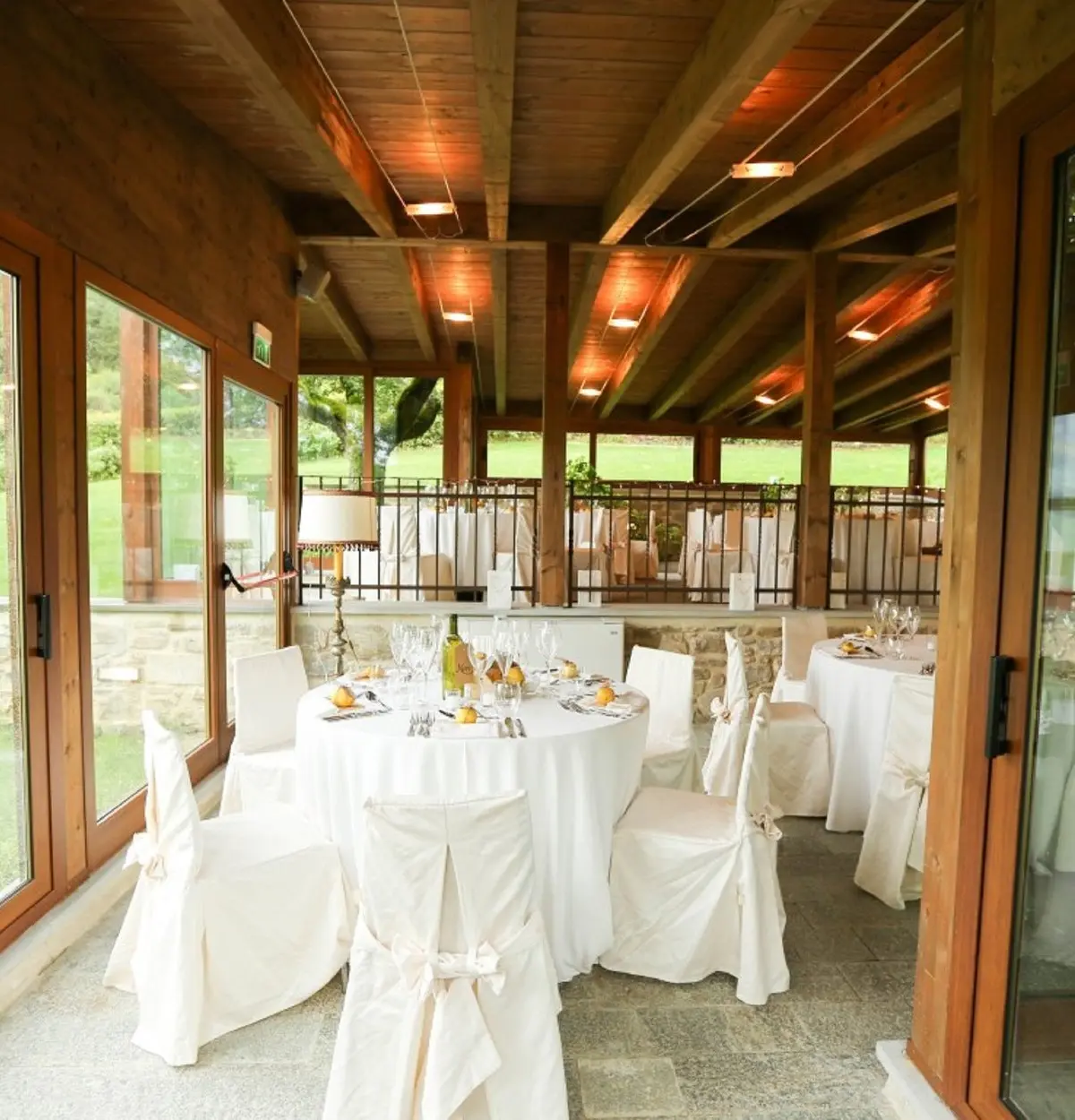 The glazed loggia set with white-clothed tables above the valley