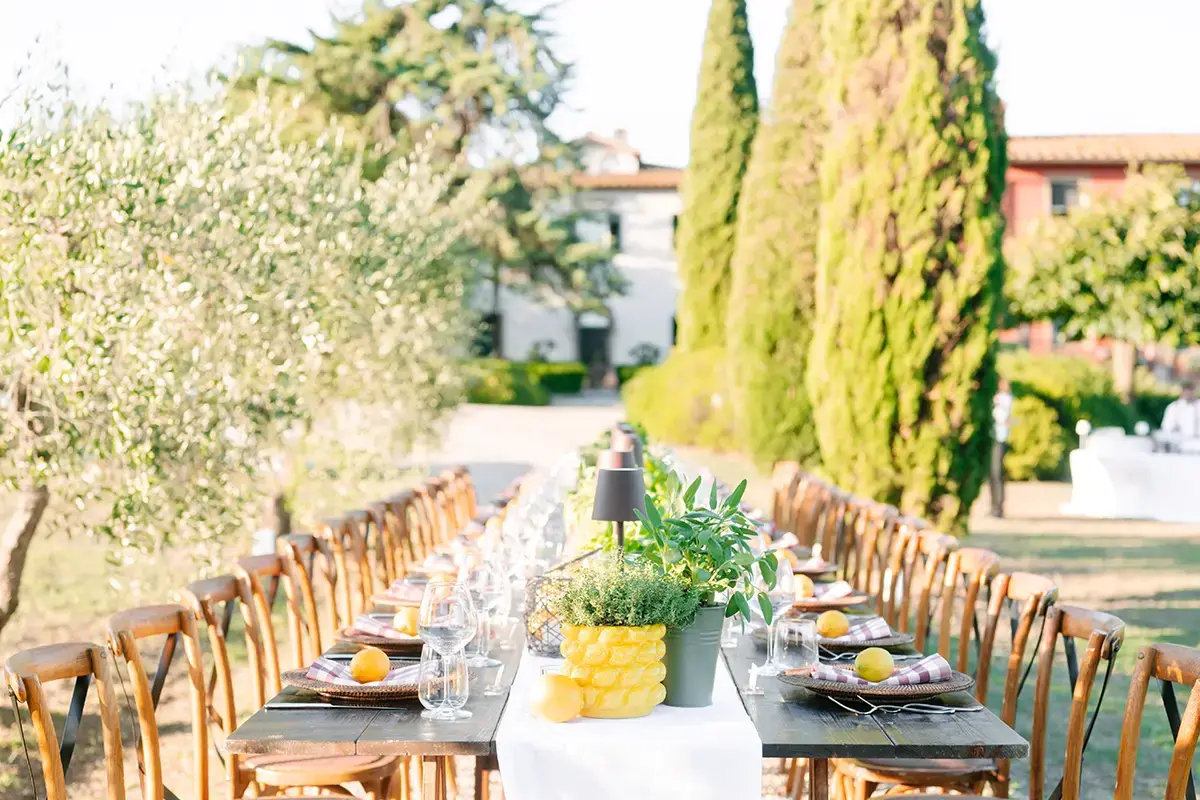 The long table set under the olive trees, the villa behind it, an hour before the light goes