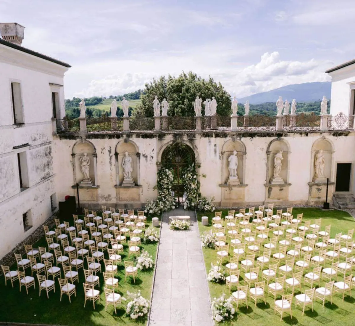 Elevated view of a ceremony inside a Palladian villa's statue-topped courtyard