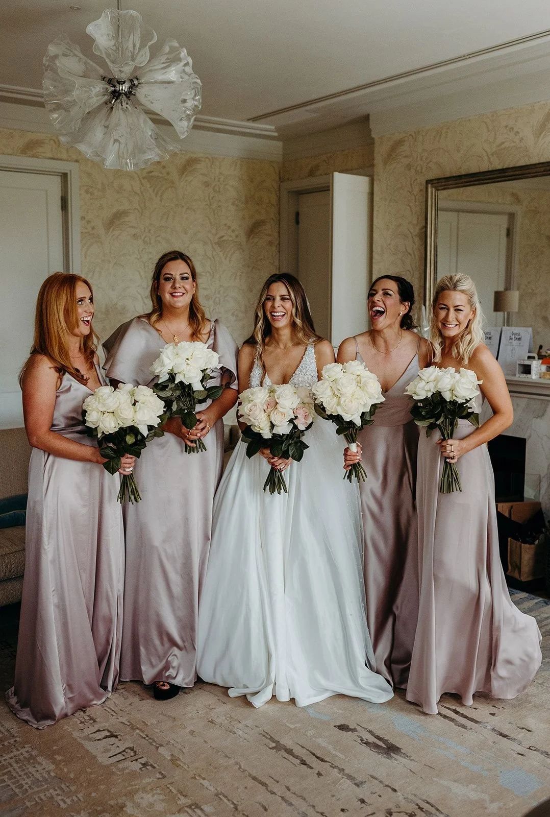 Five bridesmaids in dusty pink, holding white bouquets, Coworth Park