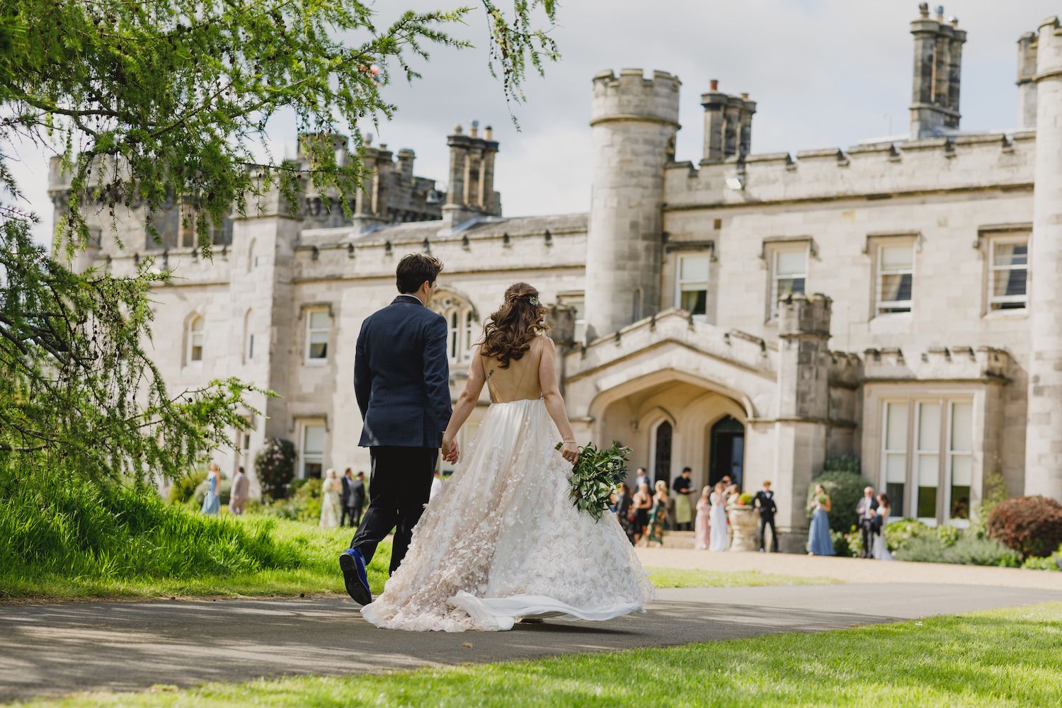 A bride and groom walking together beside the castle