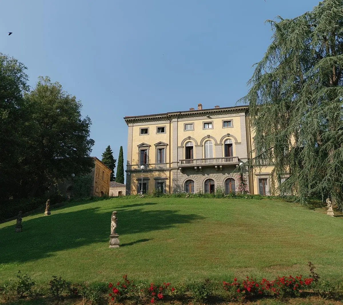 A Tuscan villa seen across its lawn, a cedar to one side