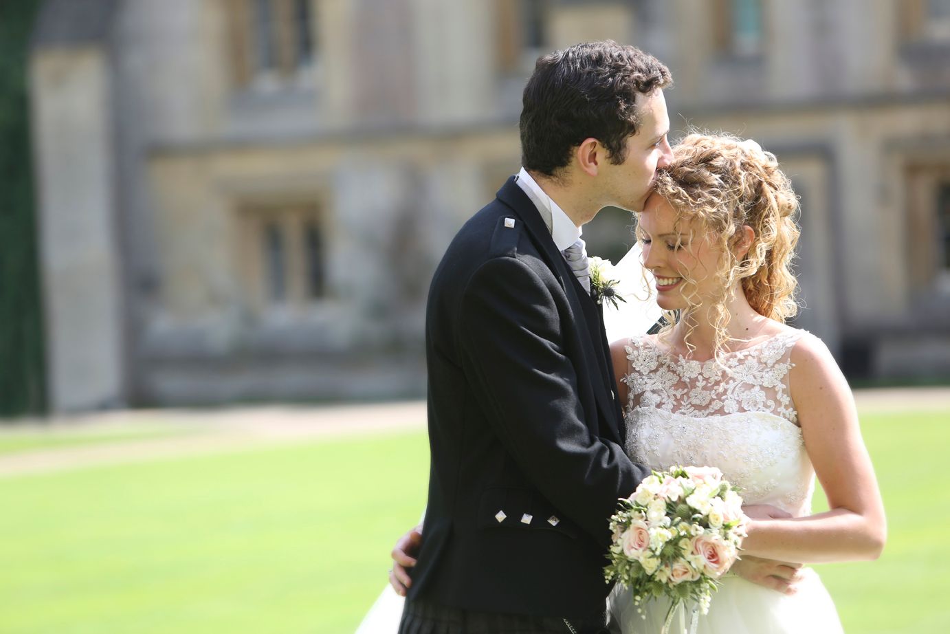 A groom resting his forehead against his bride's, castle grounds