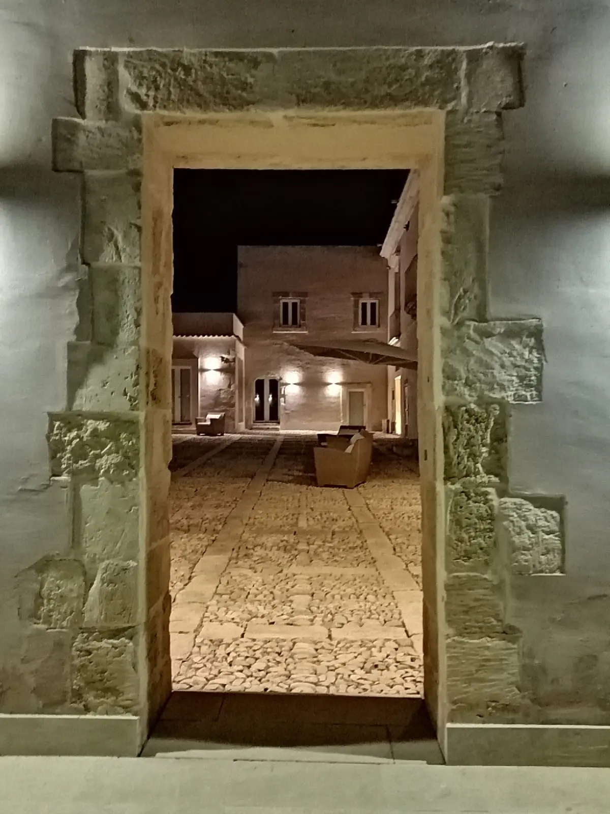 The entrance at night, a stone doorway opening onto a lit interior, Ballium Luxury Relais, Avola, Italy
