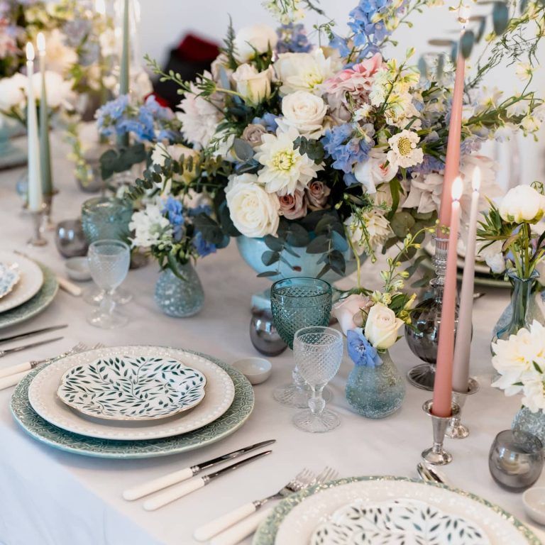 A place setting among blue delphinium and white roses