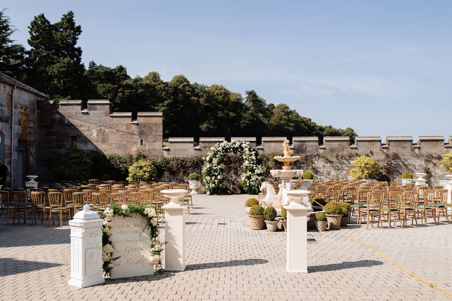 The courtyard terrace set with chairs and a floral arch for a ceremony