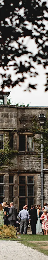 The hall's stone facade across the lawn, guests gathered