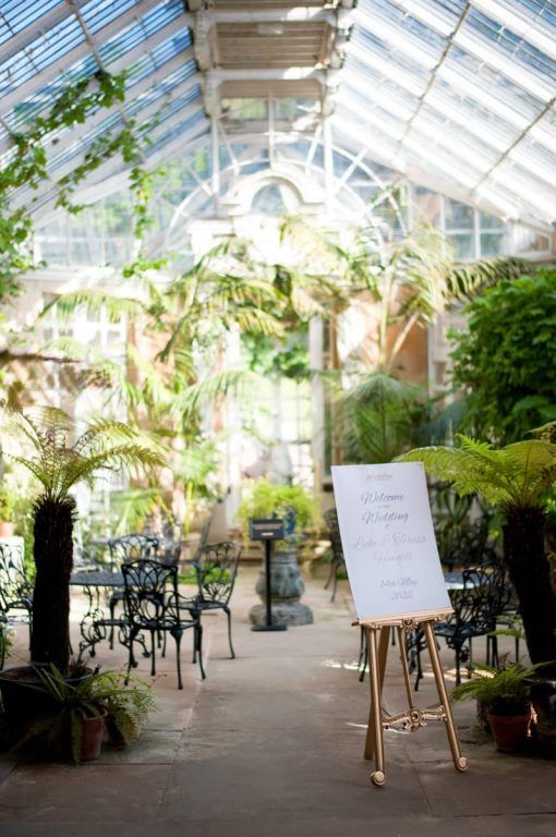 The fern-filled conservatory with a wedding welcome sign