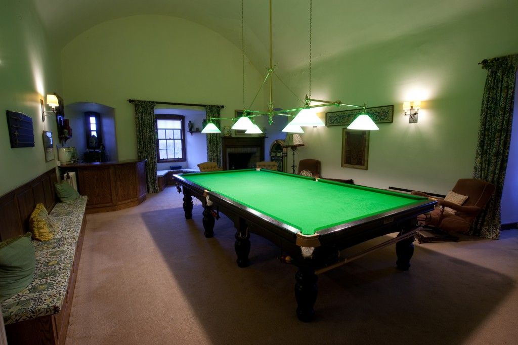 The snooker room beneath a vaulted green ceiling, a full-size table under low lamps