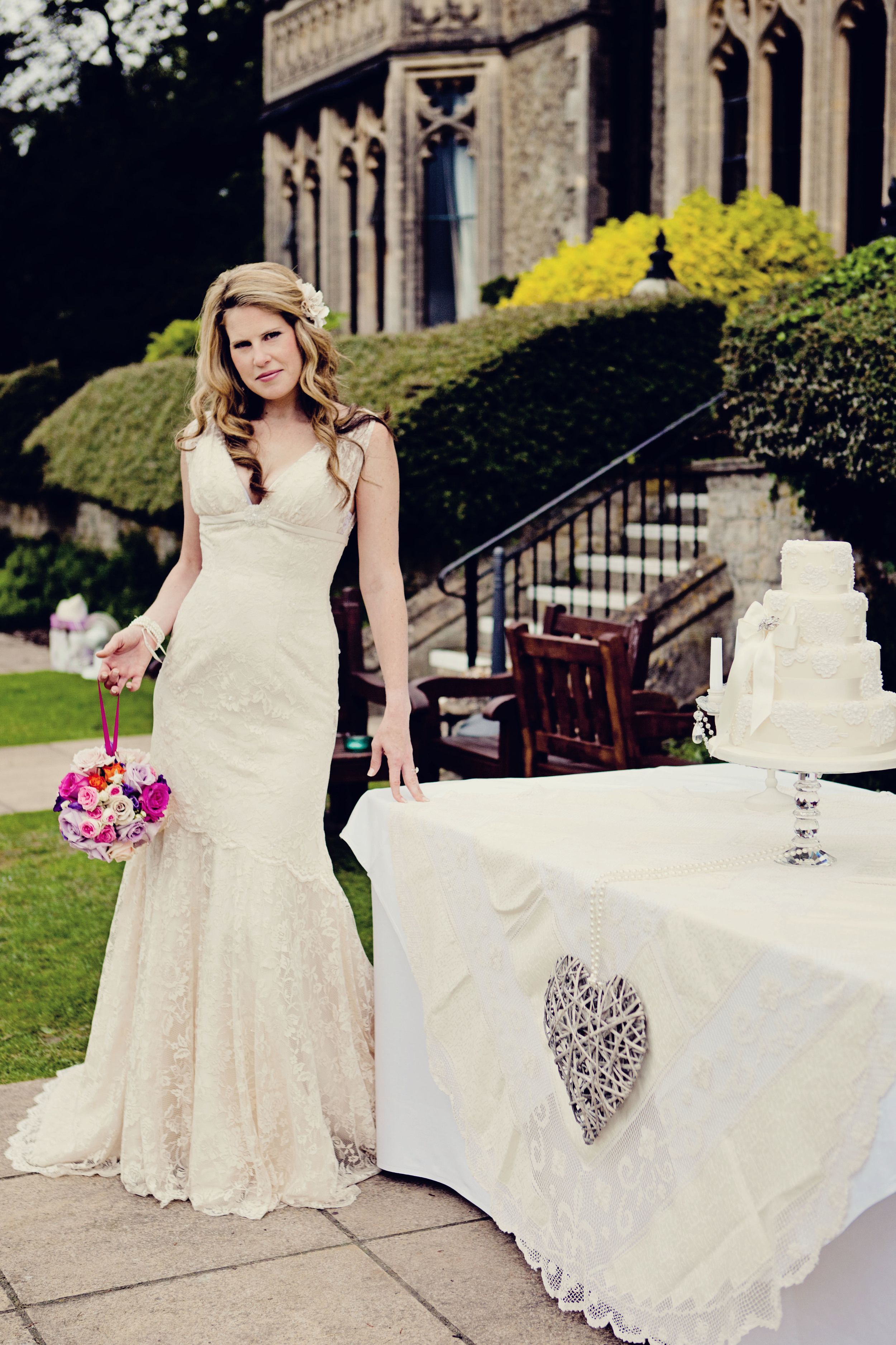 A bride in a fitted lace gown on the steps of a country house