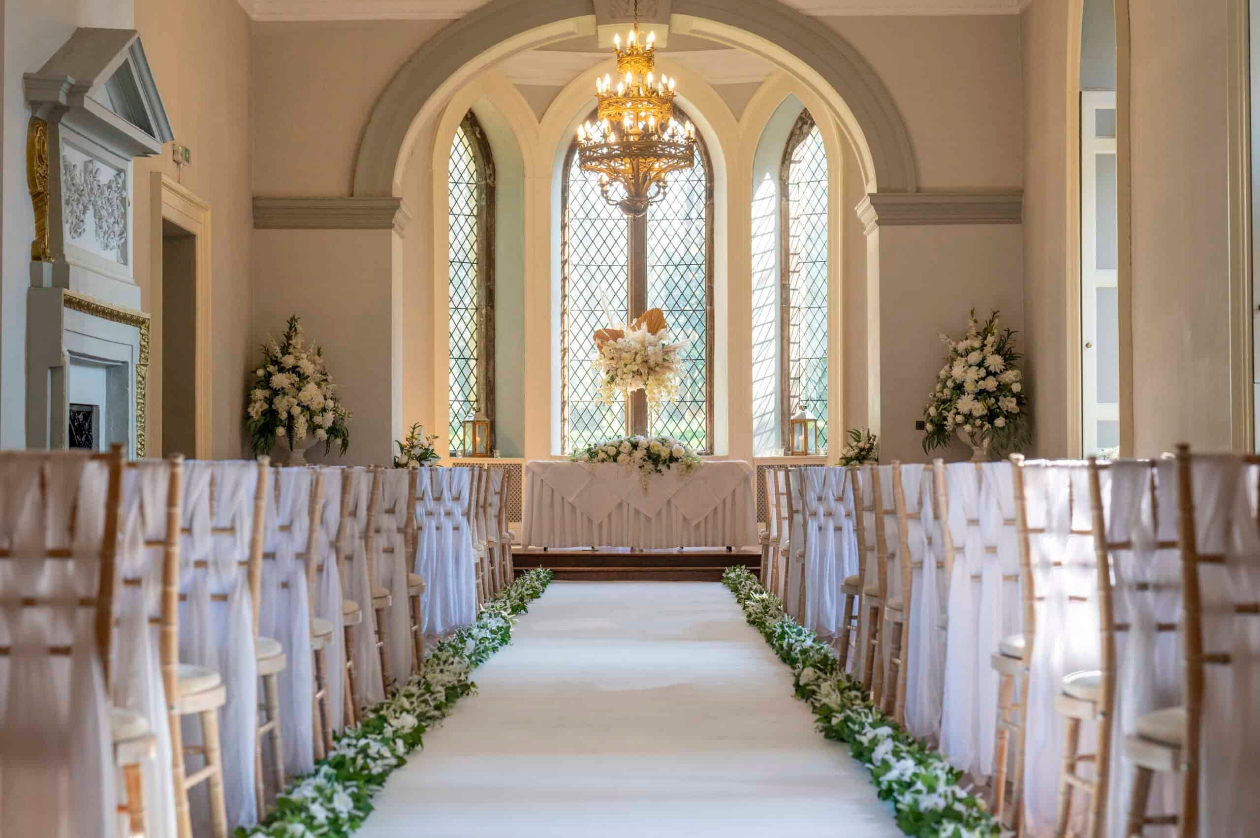 A Ballroom ceremony, a greenery-lined aisle to the registrar's table below the great arched window