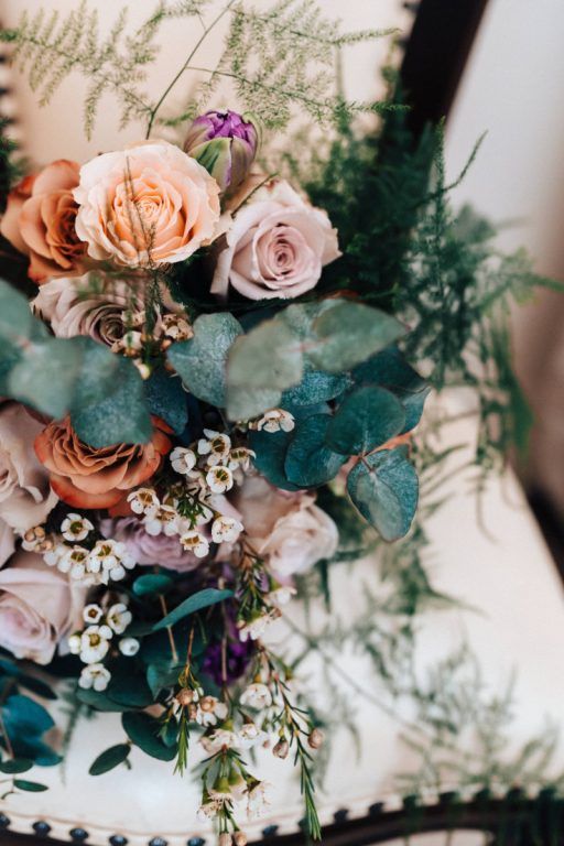 A bouquet detail in peach and mauve rose, with trailing eucalyptus