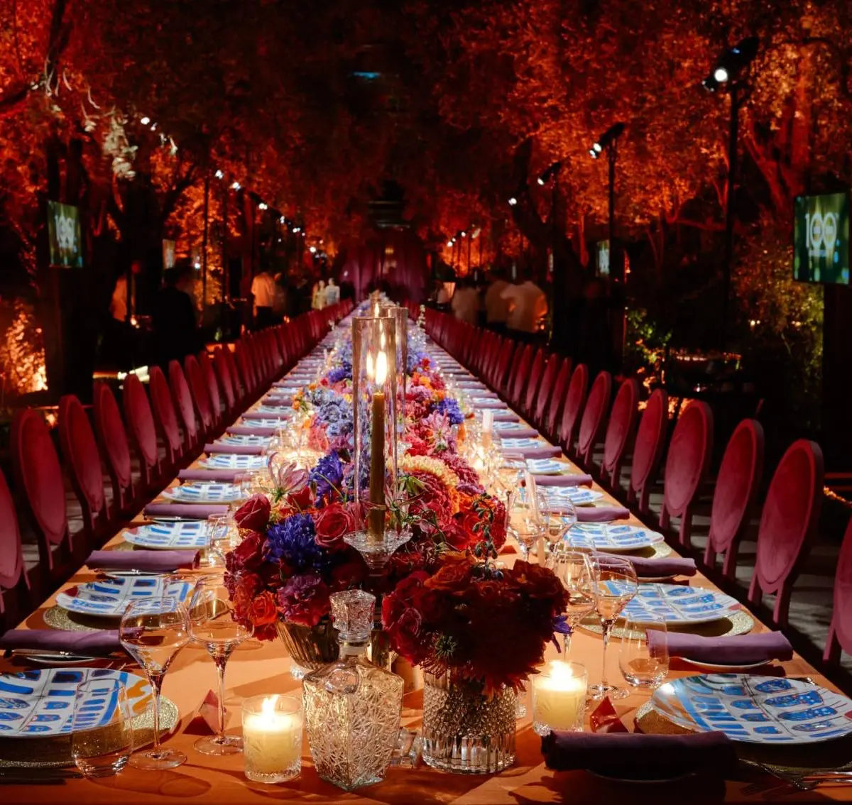 A candlelit long banquet table in the illuminated gardens