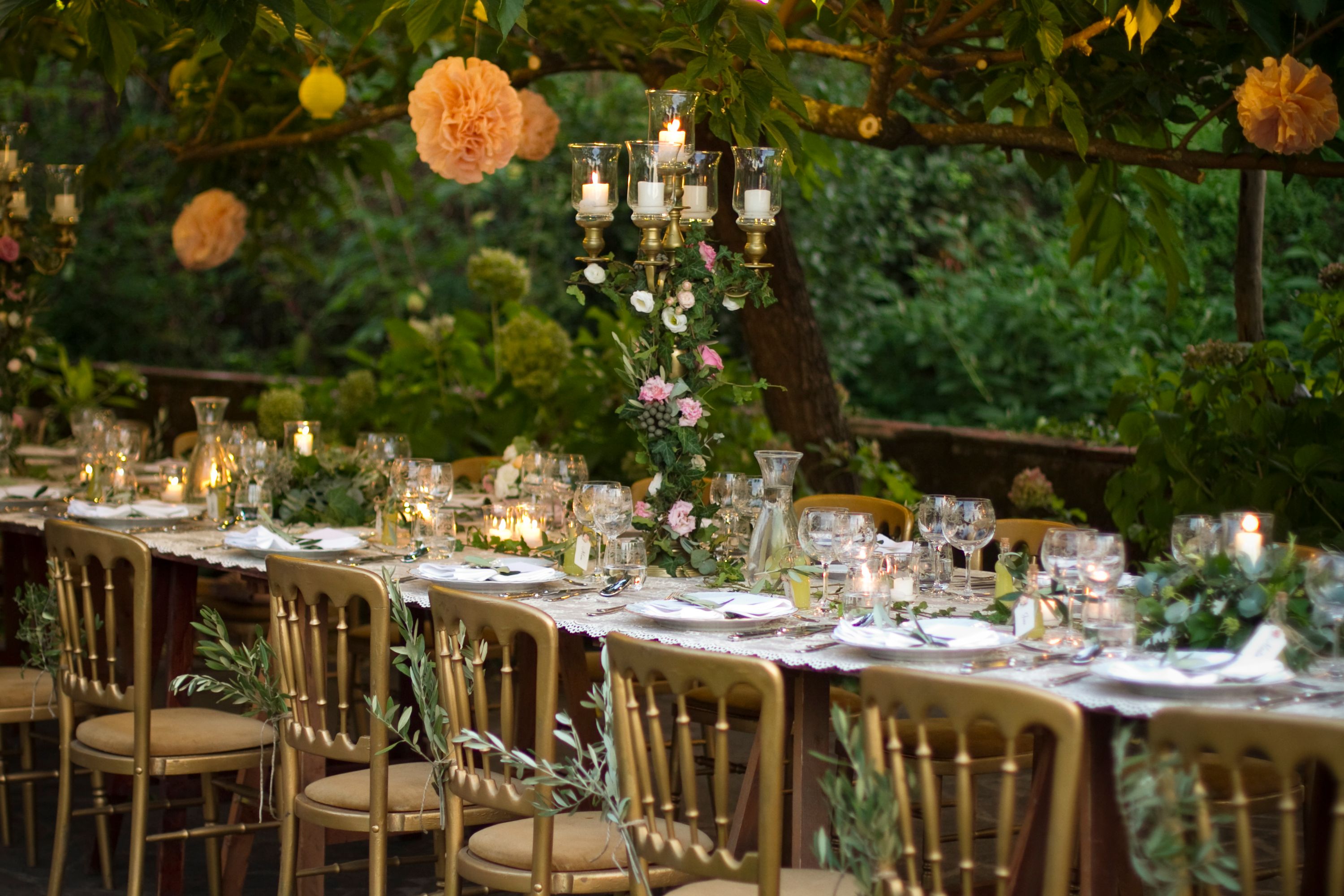 A garden reception with a long table set under olive trees, Villa Michaela, Lucca, Italy