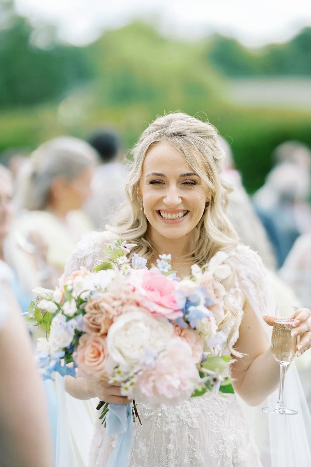A bride, mid-laugh, with a peach and blush bouquet