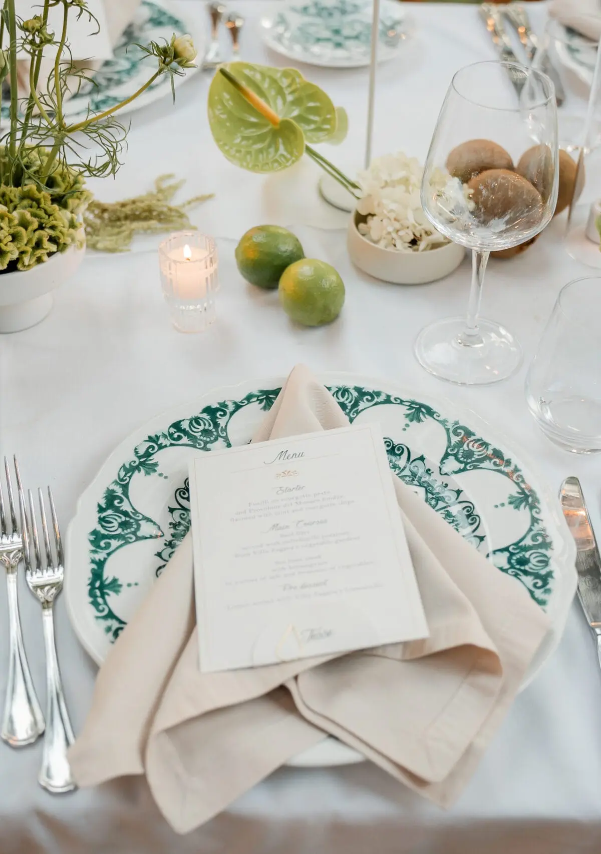 Green and white ceramics, limes and calla lilies laid on white linen