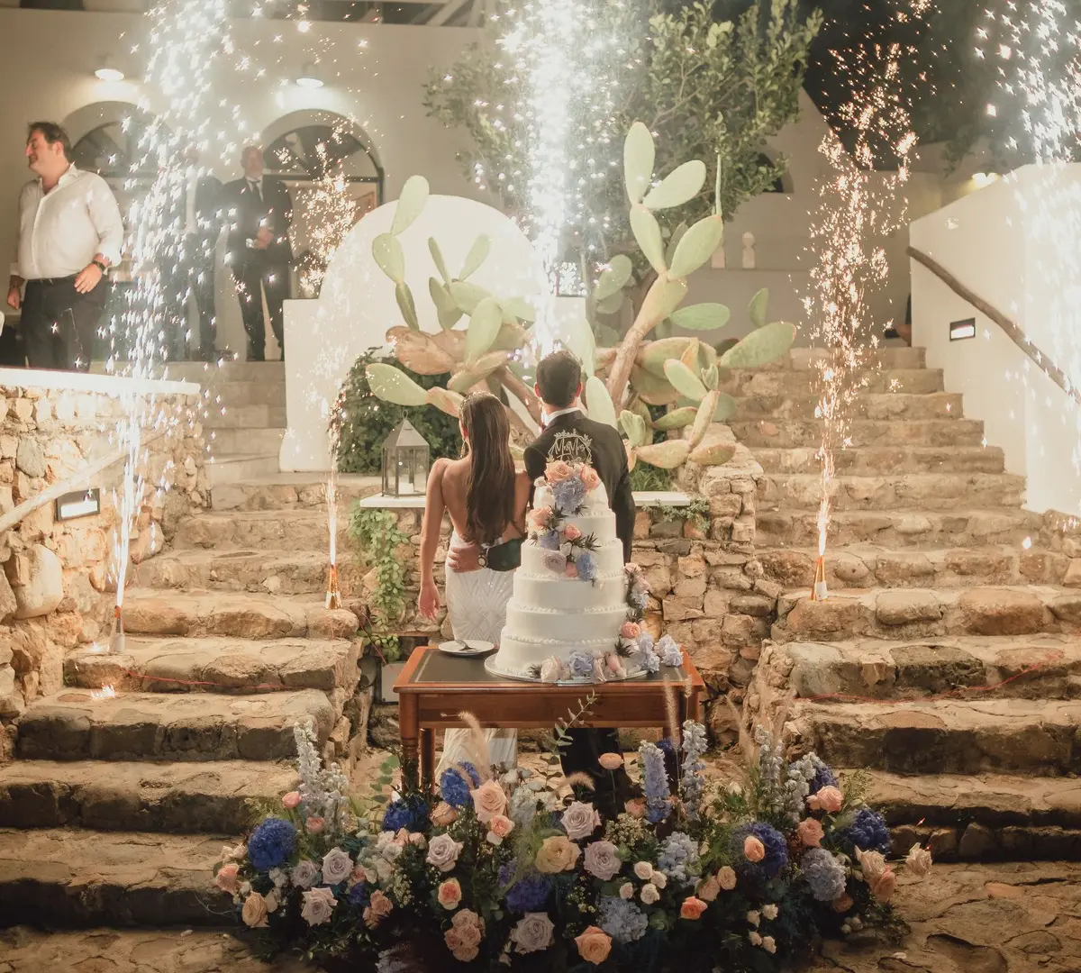 The cake cut on a stone stair between sparkler fountains