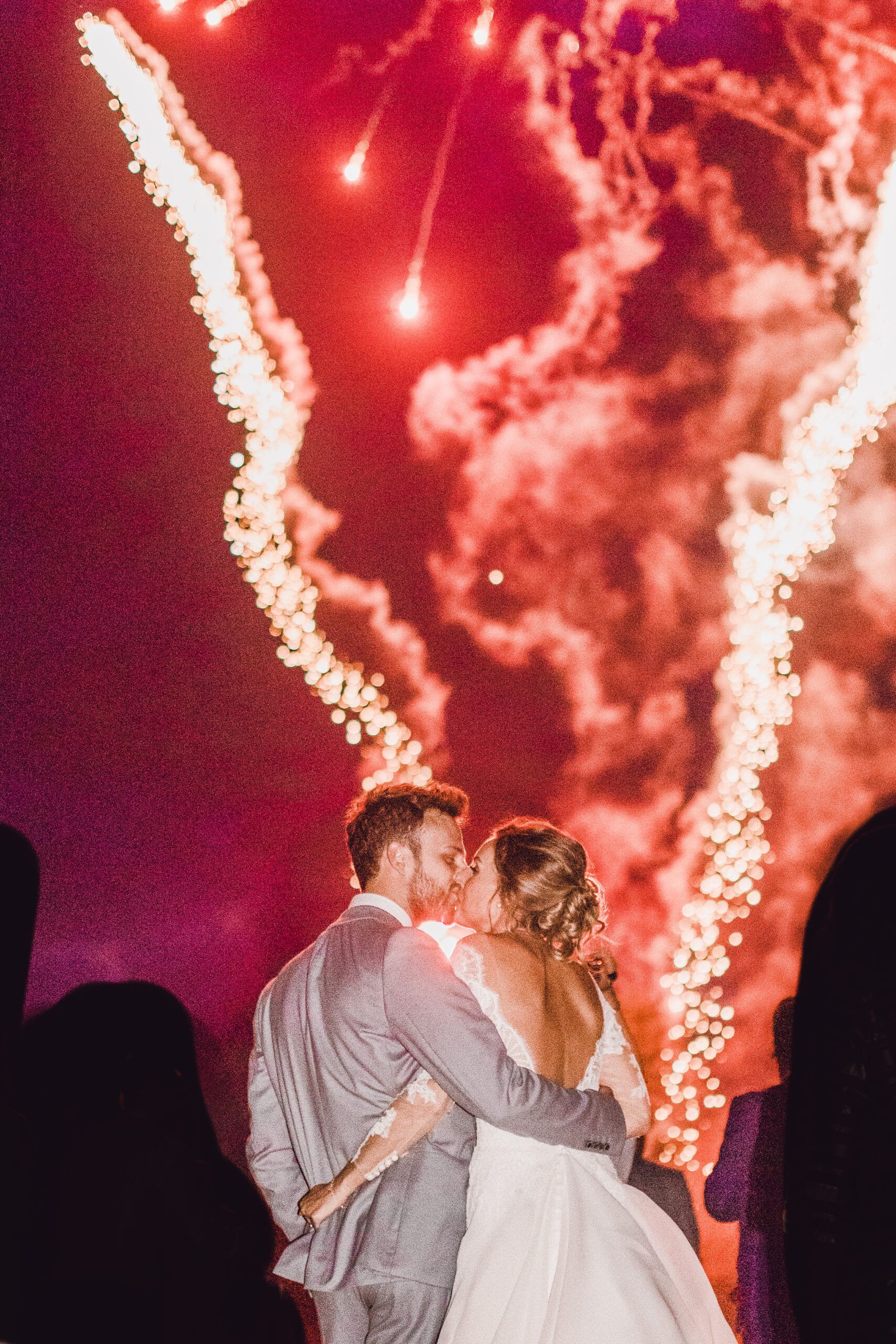 A couple embracing before a fireworks display in the grounds at night