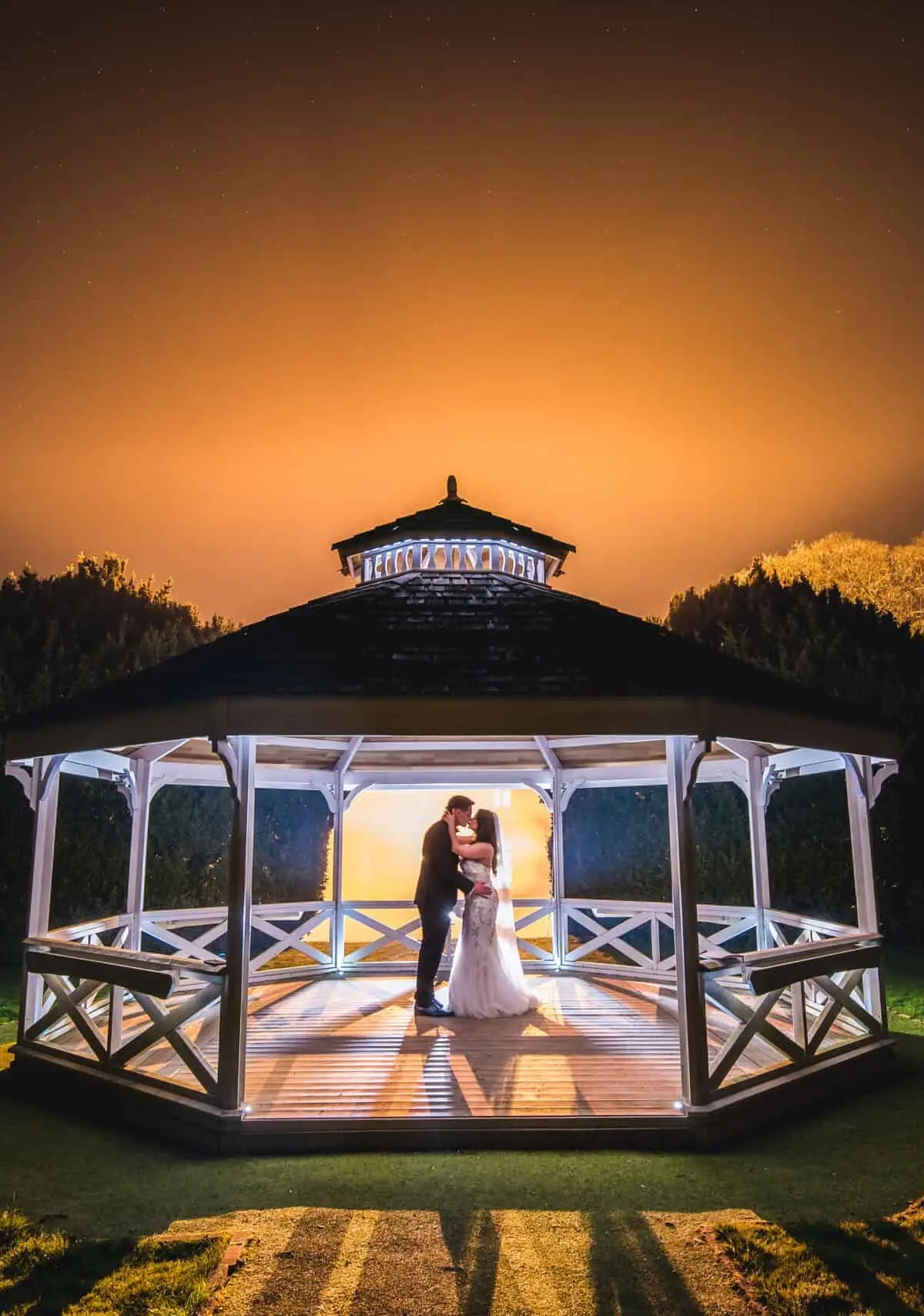 A couple in the illuminated garden Bandstand at night