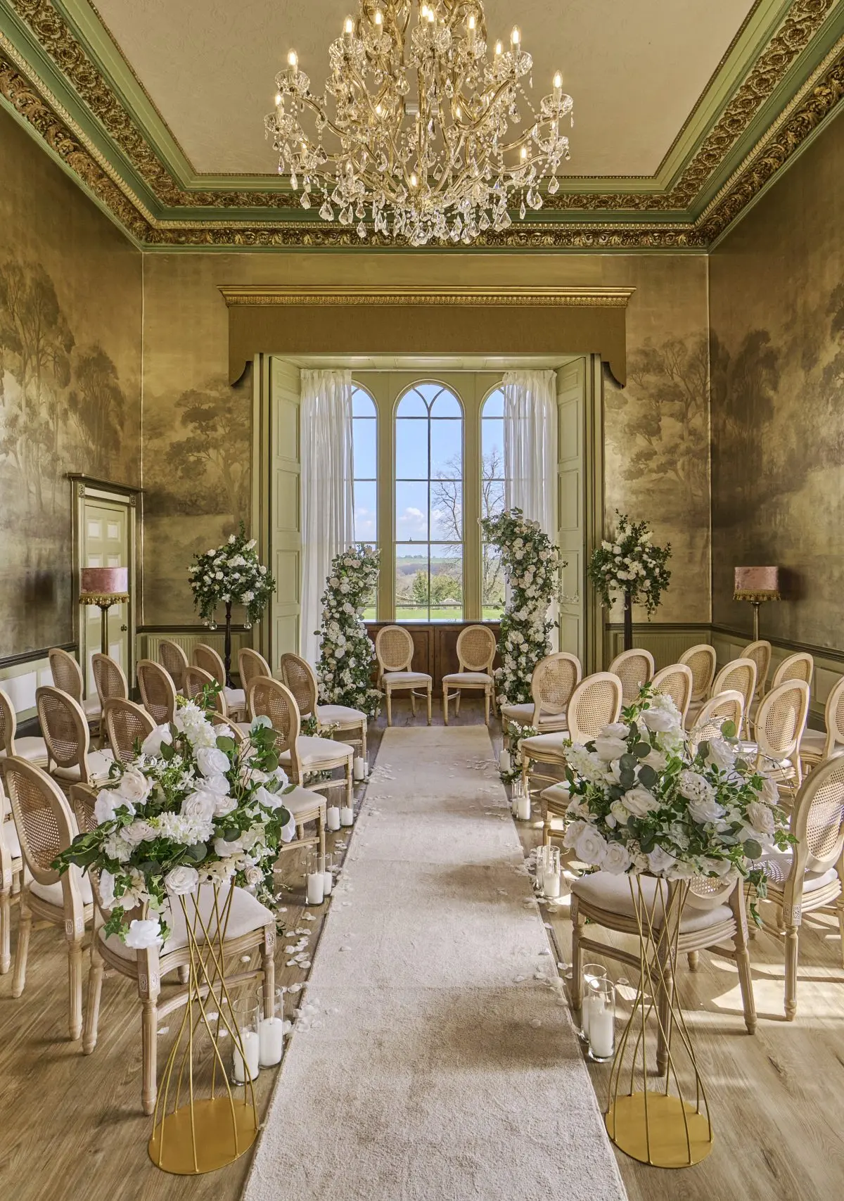 A gold-walled ceremony room set with chairs and a floral arch