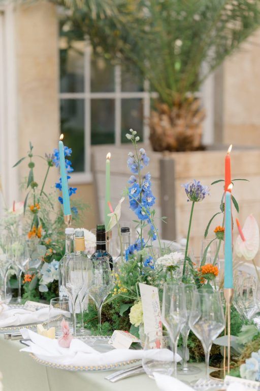 A garden reception table in delphinium, marigold and wildflower, dressed with painted candles
