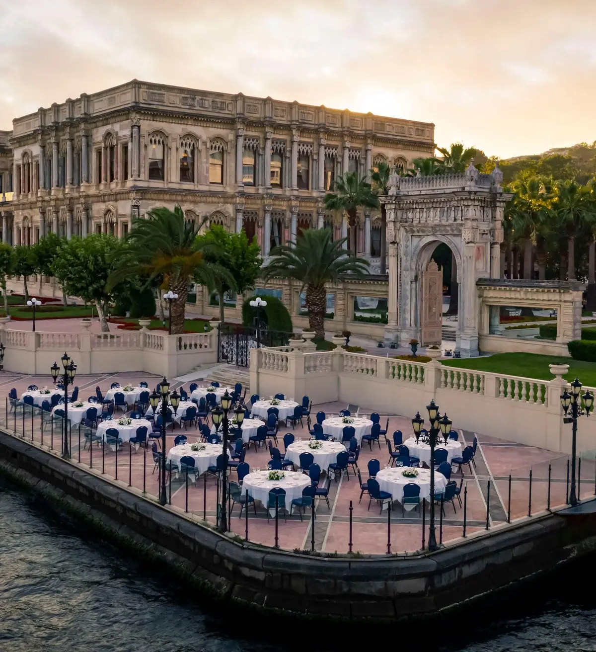 An aerial of the palace on the Bosphorus at dusk, tables set out along the waterfront terrace, Çırağan Palace Kempinski Istanbul, Istanbul, Turkey