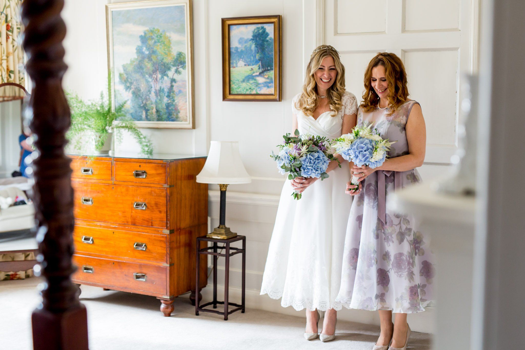 The bride and a bridesmaid by an antique dresser