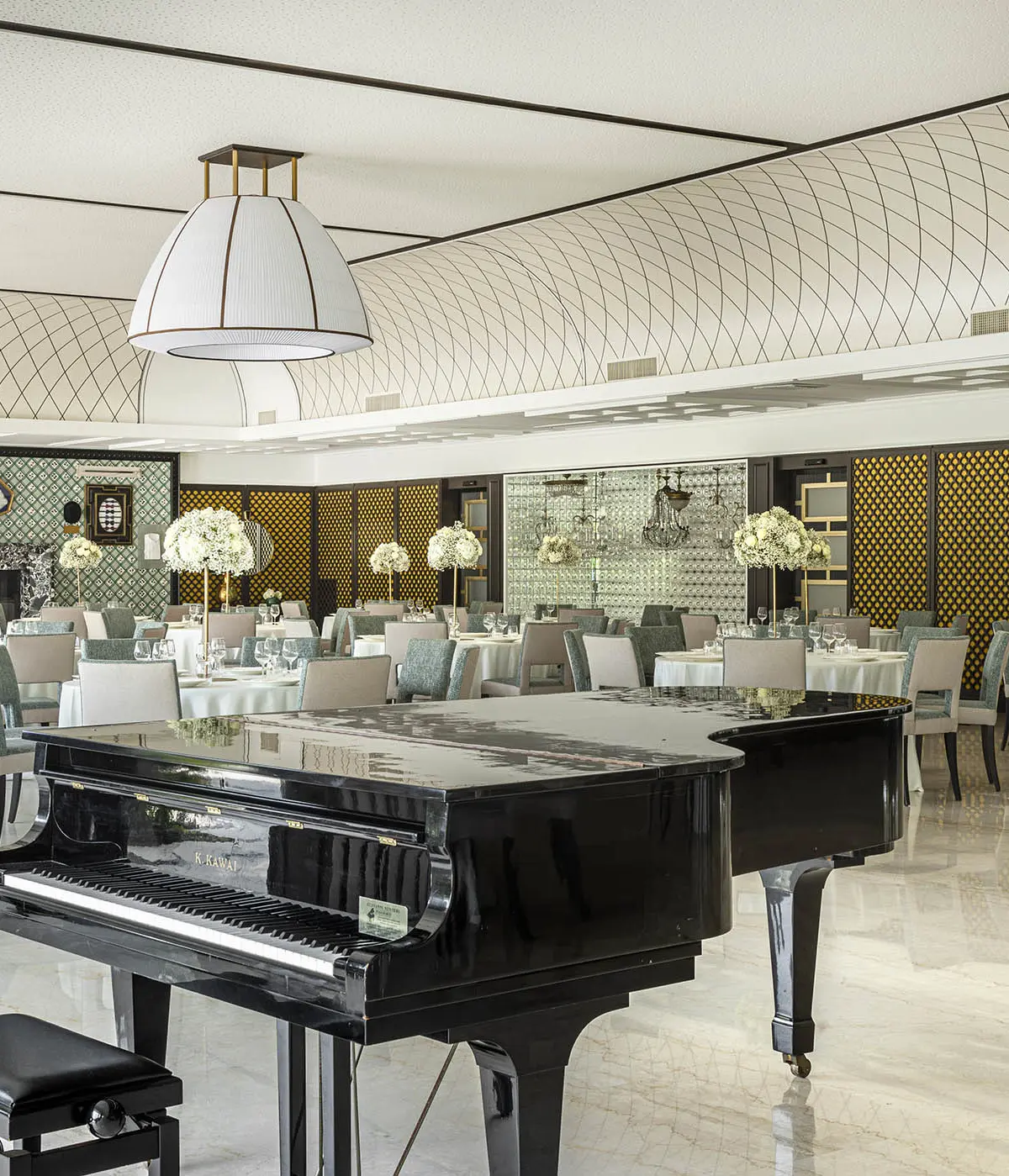 A salon set with a grand piano and round tables for a wedding