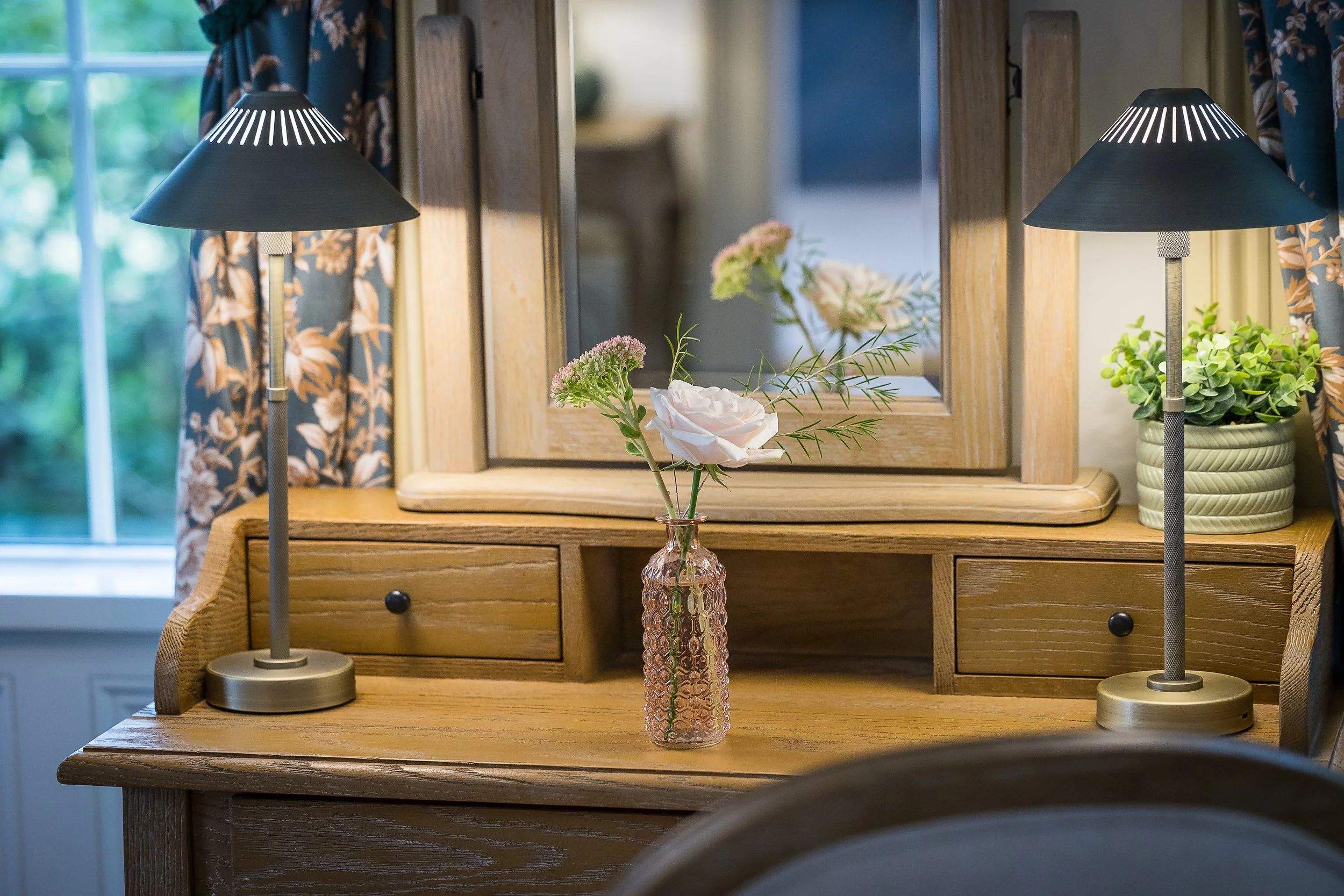 A dressing table with lamps and flowers in a guest room