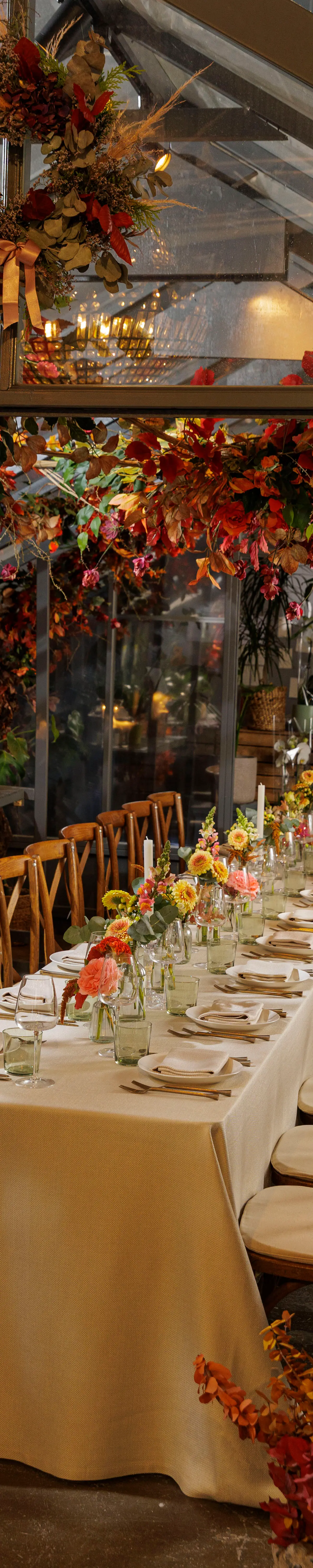 The full height of the glasshouse, flowers overhead and the table below