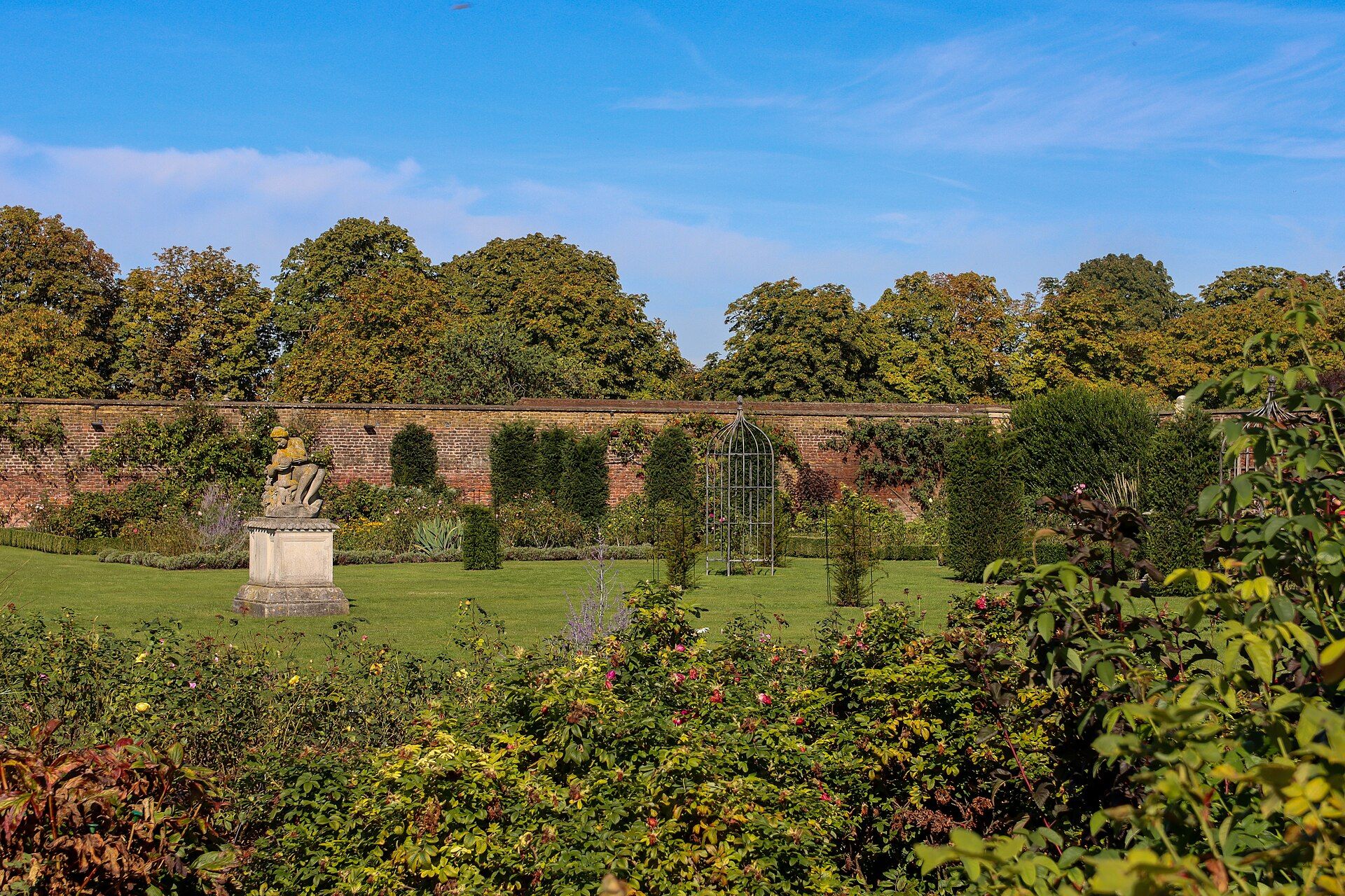 A walled garden of deep herbaceous borders and a statue in the palace grounds