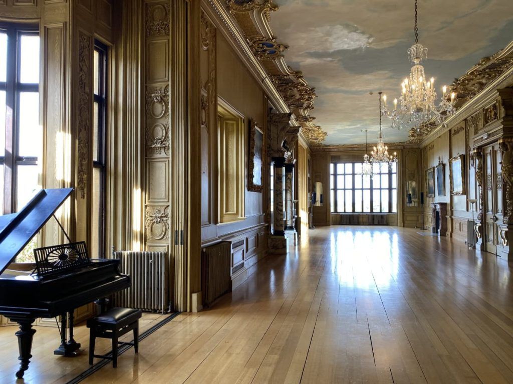 A sunlit gallery with a polished timber floor and a grand piano