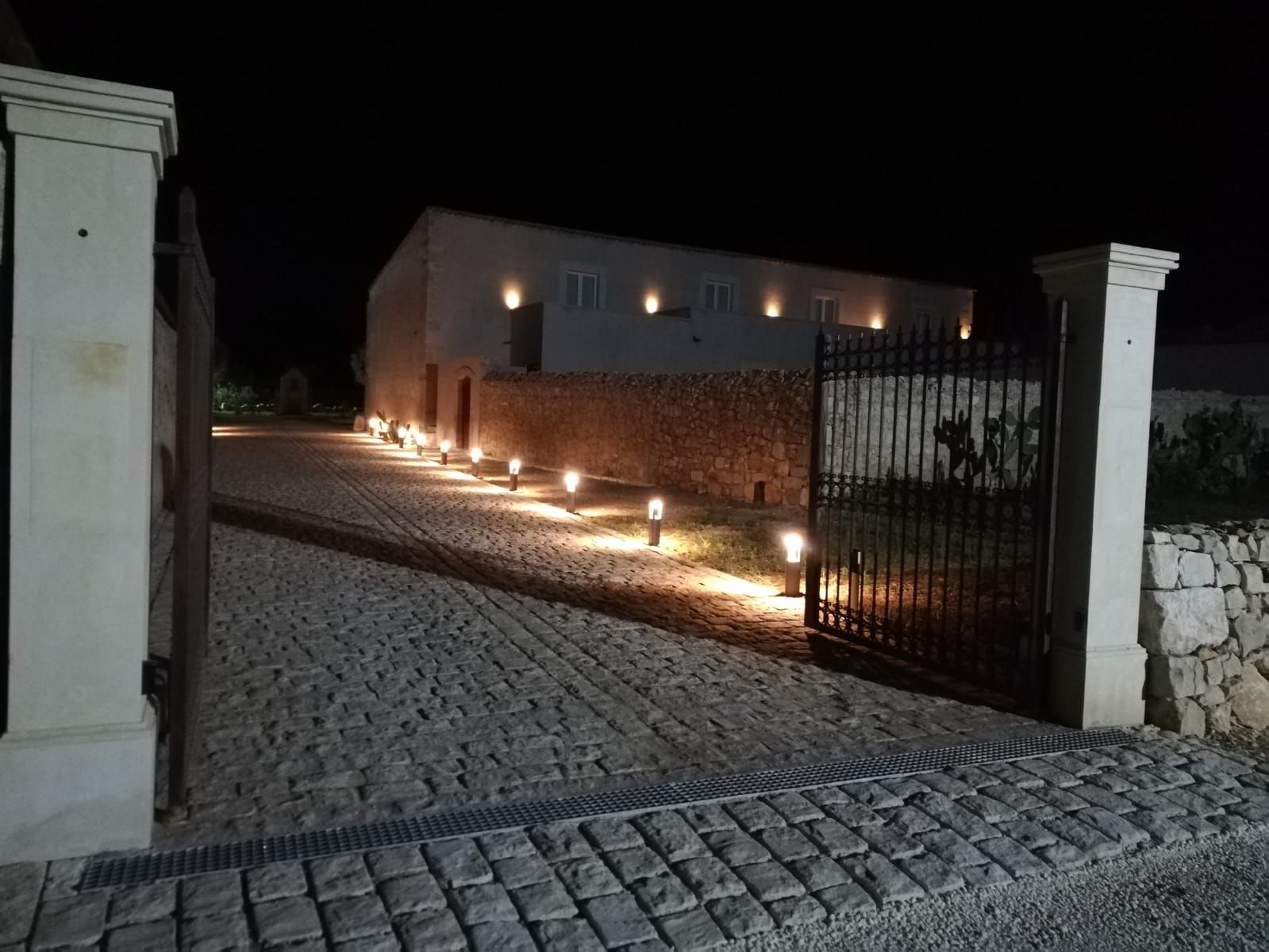 The estate gate lit by candlelight after dark