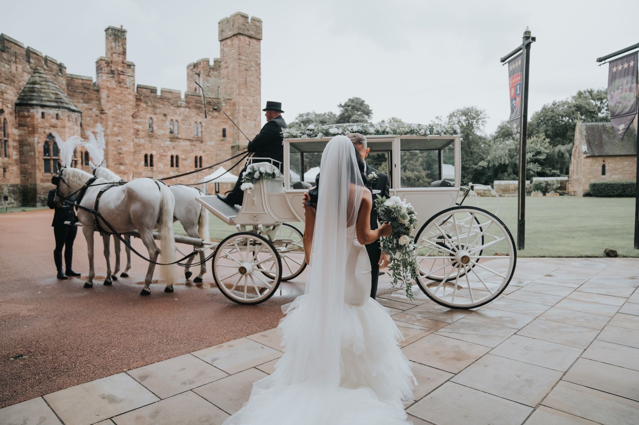 A bride steps toward a white horse-drawn carriage before the castle