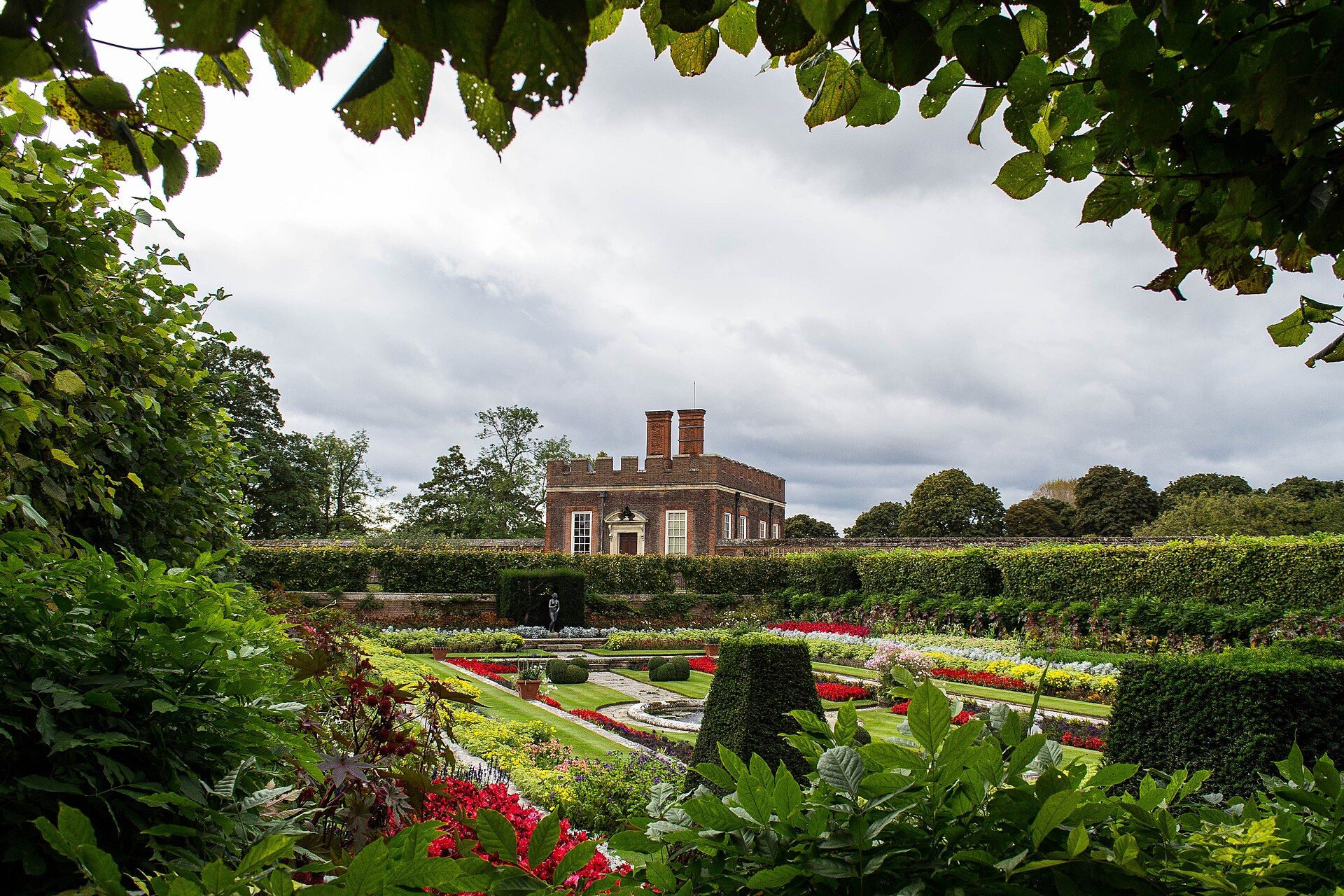 The Little Banqueting House rising beyond a formal parterre of clipped box and summer flowers